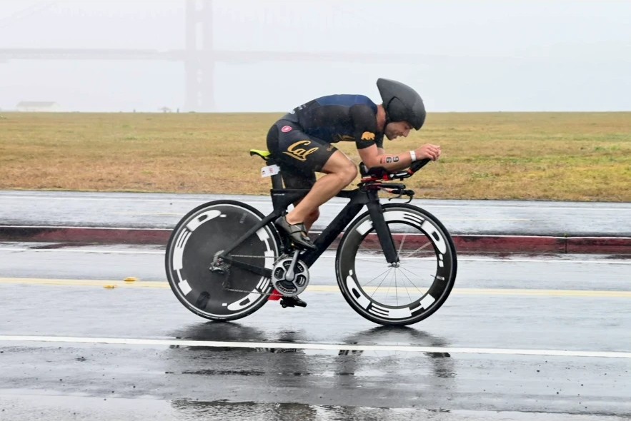 Triathlete riding a time-trial bike on a wet race course