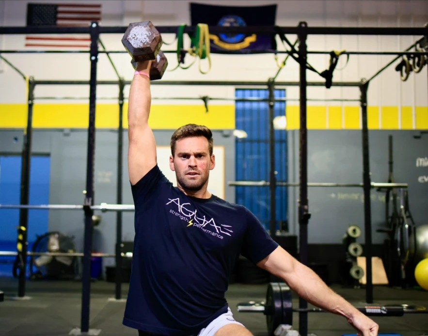 Coach Jack Brown pressing a dumbbell overhead in the Aqua Strength gym